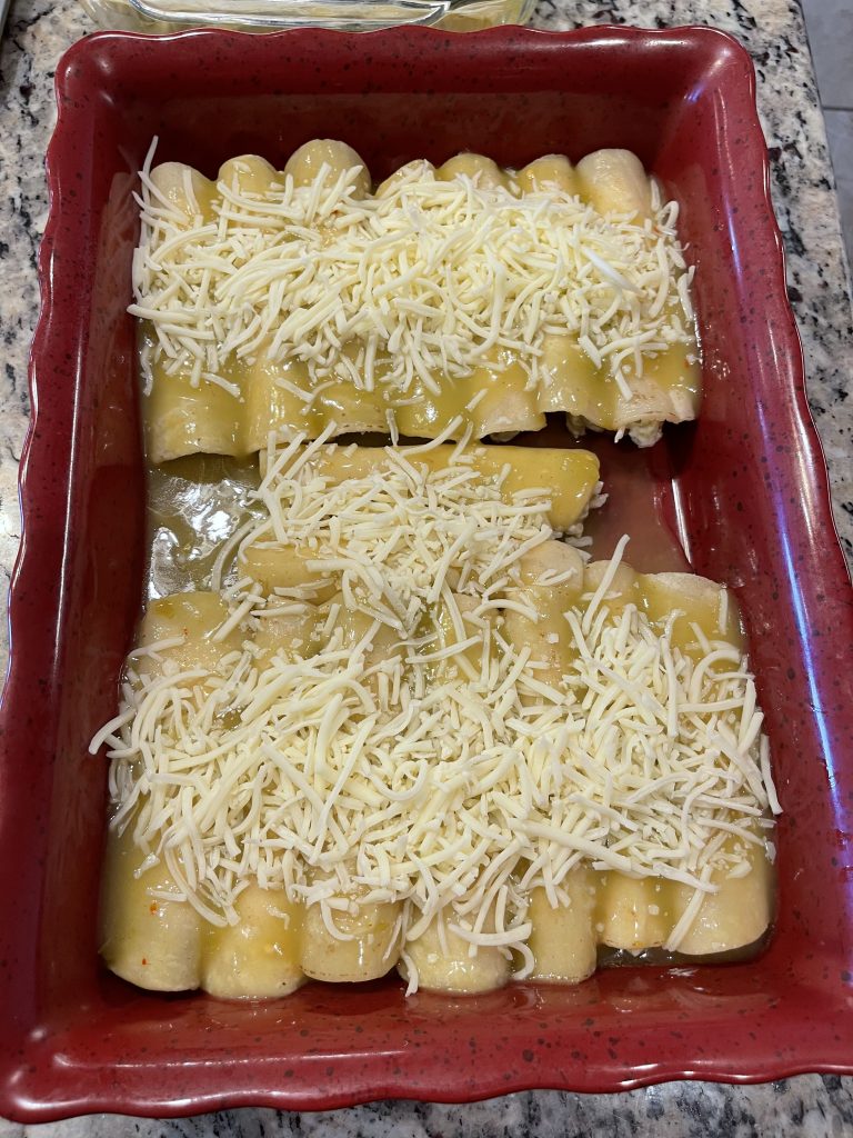 Baking Dish with Rolled Enchiladas, topped with sauce and shredded cheese