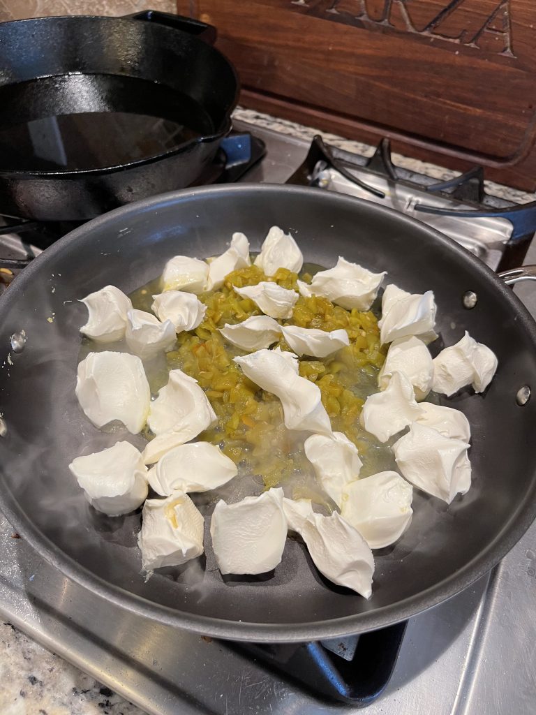 Image of Skillet heating cubed cream cheese and green chilis