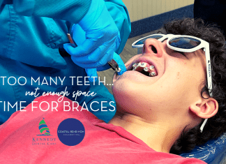 Image of a teenaged boy, wearing a dark pink t-shirt, laying in a dentists chair with white sunglasses on. A dentist is installing brackets for braces on his teeth. Title reads: Too many teeth, not enough space: Time for Braces | Kennedy Dental & Coastal Bend Mom Collective