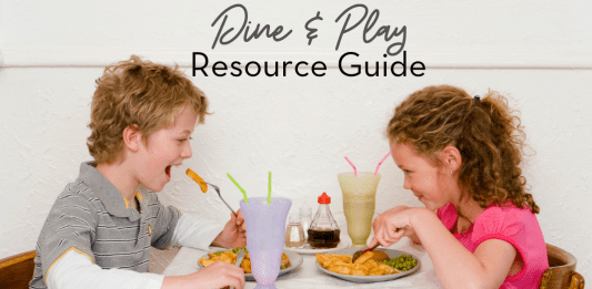 Image: A blonde haired boy wearing a gray polo shirt, sits at a table taking bite of a French fry. Across from him sits a brunette curly haired girl, also eating. Text reads: Dine & Play Resource Guide