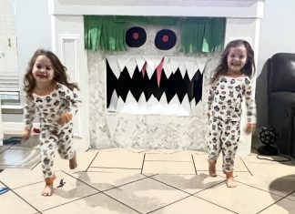 Boy-Girl twins wearing matching pajamas, standing in front of a halloween decorated white fireplace.