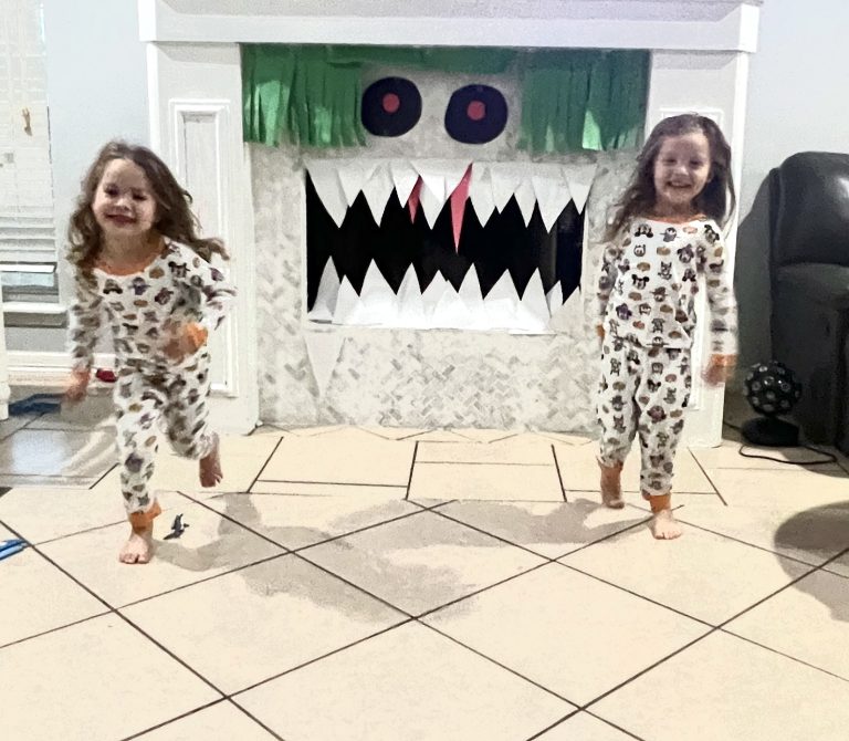 Boy-Girl twins wearing matching pajamas, standing in front of a halloween decorated white fireplace.