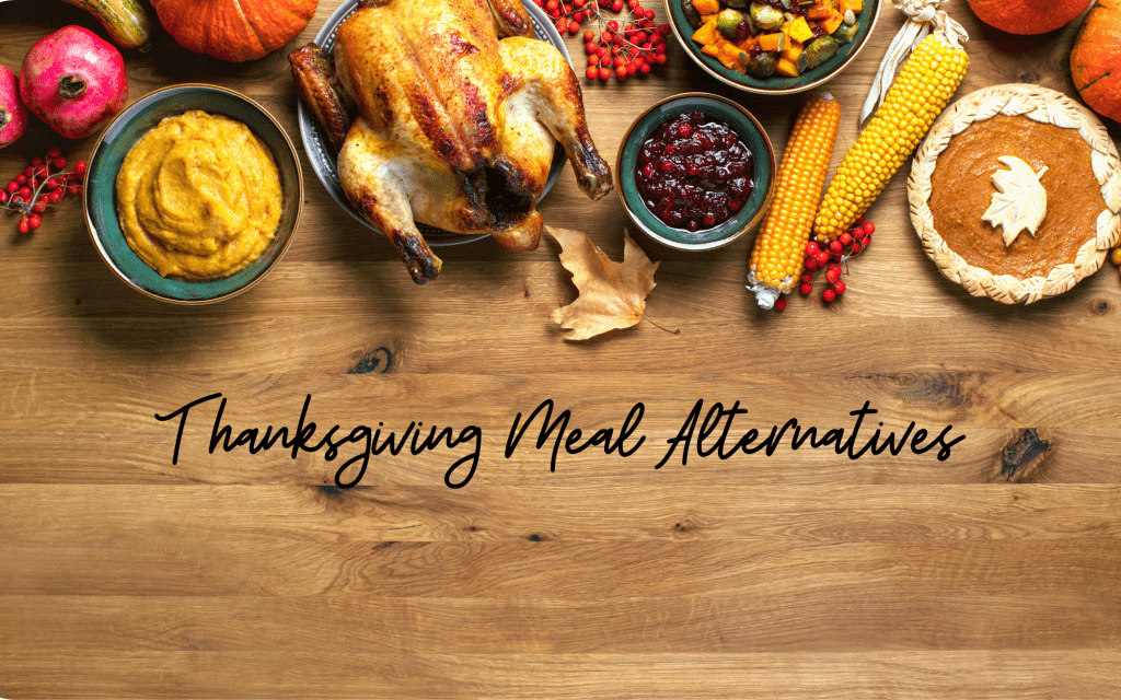 Image shows a Thanksgiving turkey, corn on the cob, cranberry sauce, and mashed sweet potatoes, all sitting on a brown wooden table. Text reads: Thanksgiving Meal Alternatives