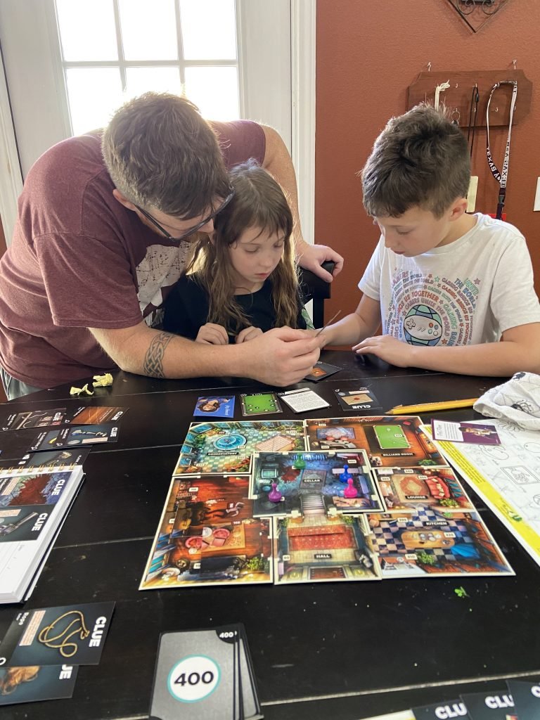 Family playin Clue: Treachary at Tudor Mansion board game