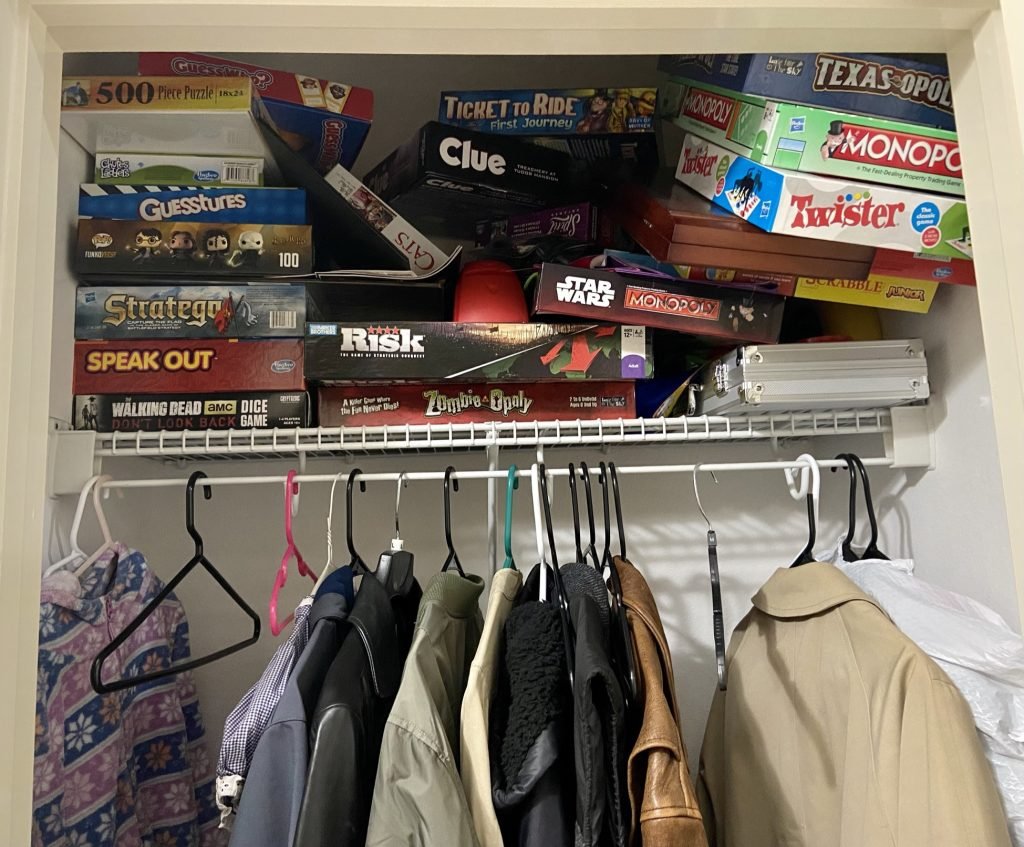 Closet full of coats and board games almost falling down 