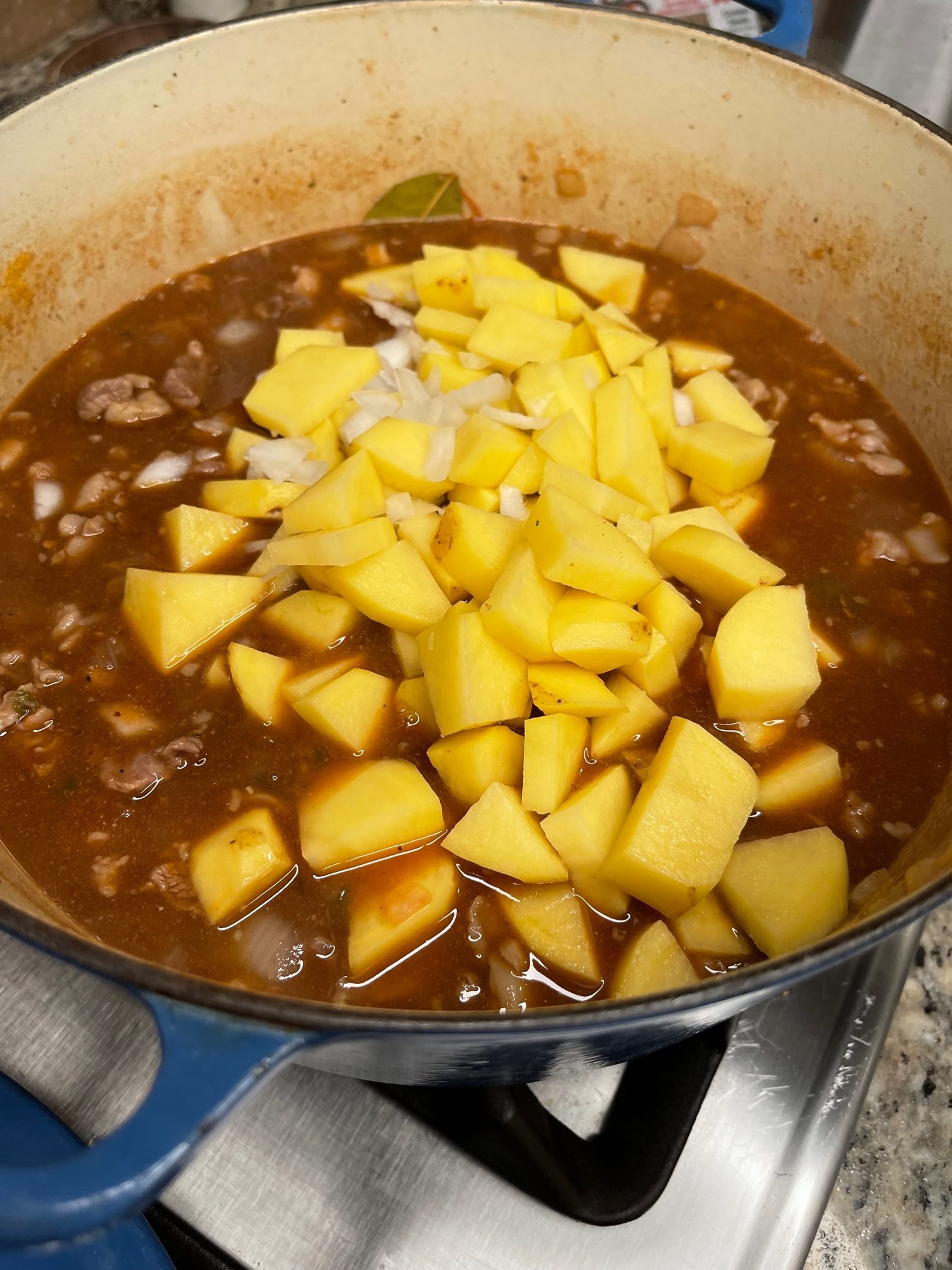 Carne Guisada being made - this picture shows the raw potatoes going into the pot